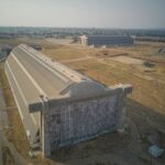 Flygbild över stora betonghangarer i ett torrt öppet landskap