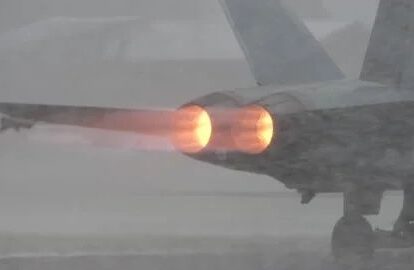 Jetflygplan med två lysande efterbrännare i kraftigt regn